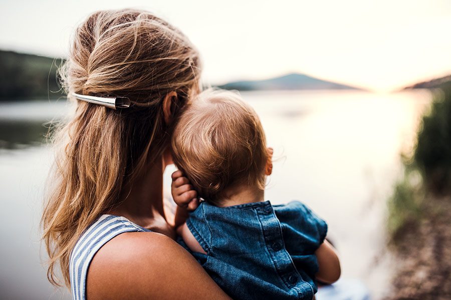 Blog - Mother Holding Baby Looking Out At Sunset Over Lake